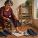 Mujer adulta sentada en un lavadero doméstico sostiene dos plantillas mientras varios pares de zapatos y calcetines se airean y secan a su alrededor.