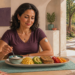 Mujer con un sensor de glucosa en el brazo desayuna yogur, huevos, aguacate, pan integral y fruta en una mesa luminosa.