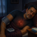 Hombre adulto acostado de noche con un manguito de presión arterial en el brazo y un tensiómetro sobre la cama, junto a un vaso de agua y un pastillero.