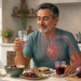 Hombre adulto sosteniendo un vaso de agua ante una mesa con remolacha, zumo de remolacha, fruta, avena y pan integral, junto a un tensiómetro y una ilustración del corazón y las arterias.