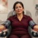Mujer sentada en una consulta médica con manguitos de presión arterial colocados en ambos brazos.