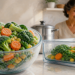 Cuenco de vidrio con verduras congeladas cubiertas de escarcha junto a un recipiente con verduras listas para cocinar, mientras una mujer sonríe en una cocina luminosa, en una comparación entre verduras congeladas y frescas.