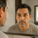 Hombre de mediana edad se observa en el espejo del baño con los ojos amarillentos y expresión seria.