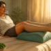Mujer adulta recostada en la cama con las piernas elevadas sobre un cojín y medias de compresión, junto a un vaso de agua y un cuenco con frutas y verduras.