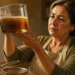 Mujer madura en una cocina, sosteniendo un recipiente de vidrio con aceite de freír usado para verificar su color y estado antes de decidir si puede reutilizarlo.