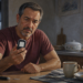 Hombre adulto observa con preocupación un glucómetro durante el desayuno, junto a una tira reactiva, un dispositivo de punción y alimentos ligeros.