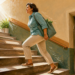 Mujer adulta subiendo unas escaleras en lugar de utilizar el ascensor, ilustrando un breve esfuerzo físico como ejemplo de los llamados snacks de ejercicio.