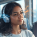 Una joven con auriculares de diadema viaja sentada en un transporte público, con efectos gráficos abstractos que emanan de los cascos representando el sonido.
