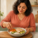 Mujer de mediana edad prepara un plato con arroz, pollo, zanahoria y calabacín en una cocina luminosa, acompañado de un vaso de agua.