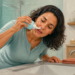 Mujer realiza un lavado nasal con una botella aplicadora sobre el lavabo del baño, dejando salir la solución por una fosa nasal mientras se inclina hacia el fregadero.