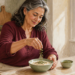 Mujer adulta añadiendo semillas verdes a un cuenco de comida en una cocina luminosa, con otro recipiente de semillas sobre la mesa.