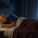 Hombre adulto durmiendo de lado en una cama durante la noche, con una lámpara encendida y la luna visible a través de la ventana.
