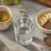 Vaso de agua junto a una taza de infusión y un bol con avena, semillas de chía y rodajas de plátano sobre una mesa.