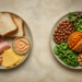 Dos platos vistos desde arriba sobre una superficie clara: uno con pan blanco, embutidos, queso y una salsa cremosa, y otro con frijoles, verduras de hoja, tomate, nueces y batata asada.