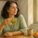 Mujer adulta sosteniendo una taza de infusión de hierbas junto a una ventana, con una taza de café y cítricos sobre la mesa.