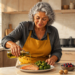 Mujer mayor vierte aceite de oliva sobre un plato con salmón y brócoli en una cocina, junto a frutos rojos y nueces.