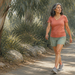 Mujer adulta caminando por un sendero arbolado al aire libre, con ropa deportiva y expresión tranquila, en una escena relacionada con el picor en las piernas durante el ejercicio.