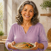 Mujer mayor sonriente sostiene un plato con pescado, garbanzos y verduras en una cocina luminosa, alimentos relacionados con el aporte de zinc, selenio y yodo.