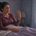 Mujer adulta sentada en la cama al despertar observa una de sus manos levantada, en una escena relacionada con el hormigueo en las manos durante la mañana.