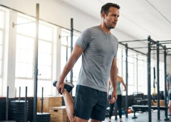 Alongamento de quadríceps em pé com técnica correta: estabilização do core, joelhos alinhados e postura equilibrada. Esse exercício melhora a amplitude de movimento e prepara os músculos para treinos de alta intensidade.