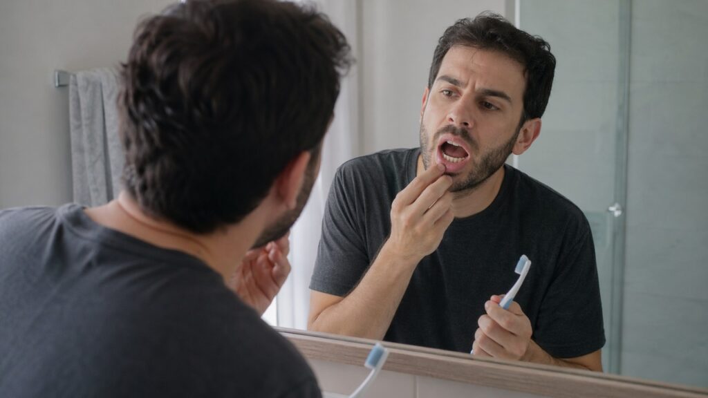 Pessoa observa sinais de candidíase oral em uma cena de cuidado precoce.